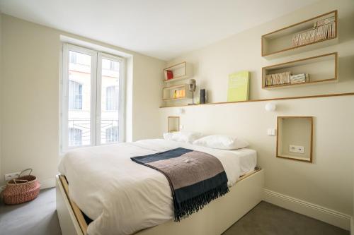 une chambre blanche avec un grand lit et une fenêtre dans l'établissement Elegant and Modern Parisian Charm, à Paris