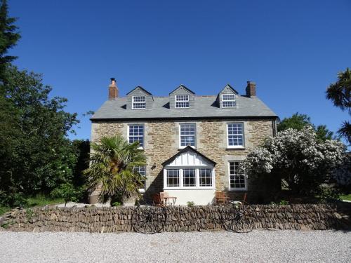 a large stone house with a stone fence in front of it at Pengelly Farmhouse B&B in Truro
