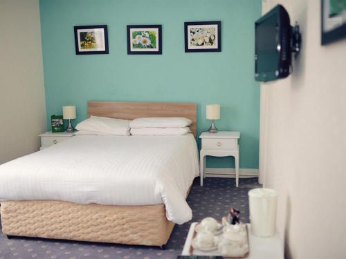 1 dormitorio con 1 cama blanca grande y 2 mesas en Park Hill Hotel, en Lowestoft