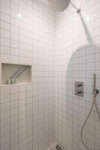 La salle de bains est pourvue de carrelage blanc et d'une douche. dans l'établissement Elegant and Modern Parisian Charm, à Paris