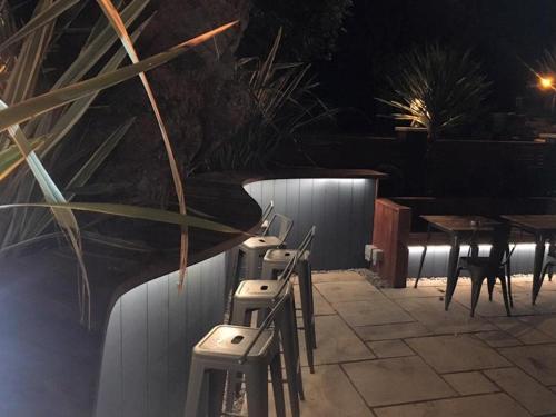 eine Reihe von Stühlen und Tischen auf einer Terrasse in der Nacht in der Unterkunft Oxgang Kitchen Bar & Rooms in Grangemouth