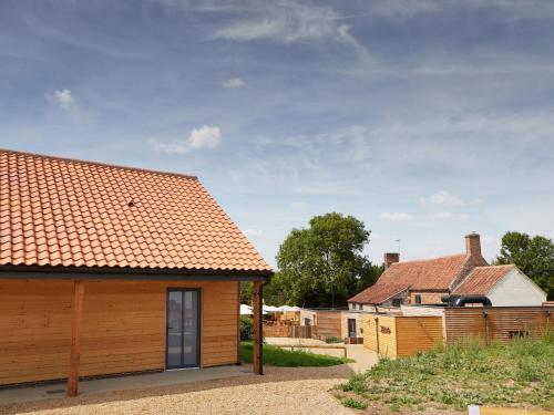 een houten huis met een rood dak bij The Pig Shed Motel in Castle Acre