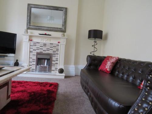 a living room with a leather couch and a fireplace at The Heidi Bed & Breakfast in Southport