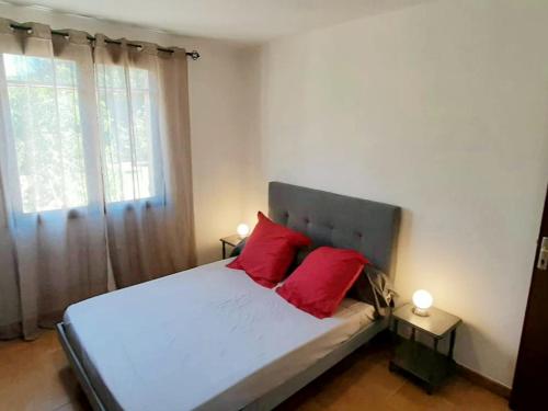 a bedroom with a bed with red pillows and a window at Gite libecciu in Pietracorbara