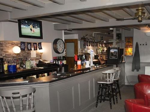 un bar con taburetes y un reloj en la pared en The Queens Head, en Oxford