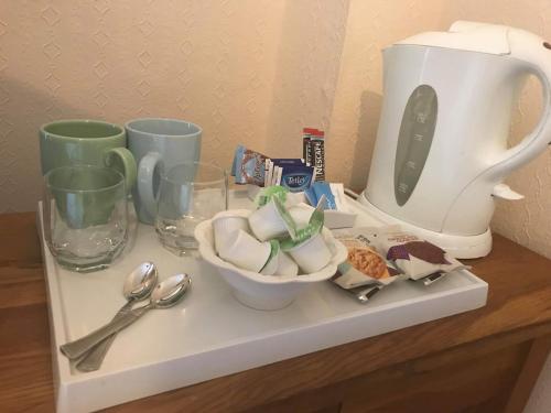 a counter with a coffee maker and cups and spoons at The Pavilion Guest House in Millom