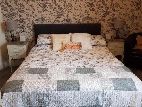 ein Bett mit einer Decke und Kissen darüber in der Unterkunft The Pavilion Guest House in Millom