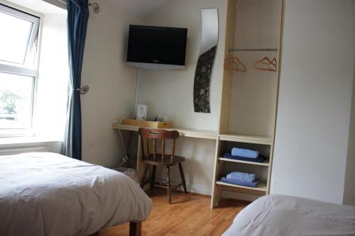 a bedroom with a bed and a desk with a television at The Plough Inn in Swindon