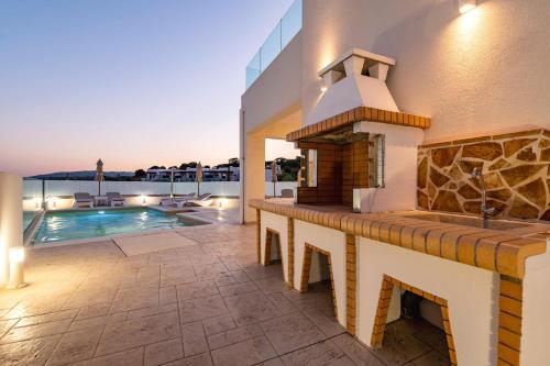 a patio with a fireplace next to a swimming pool at Villa Eventide in Gennadi
