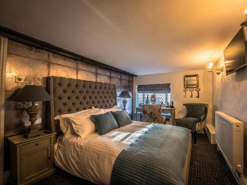 um quarto com uma cama grande e uma cadeira em The Royal Standard em Ely