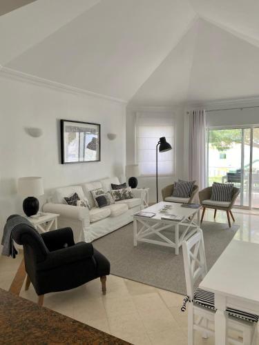 a living room with white furniture and a table at Beautiful apartment for rent in Quinta do Lago with excellent resort facilities close to lake and beach. in Quinta do Lago