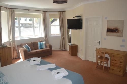 ein Hotelzimmer mit einem Bett, einem Sofa und einem TV in der Unterkunft The Sheldon B&B - FREE private parking in Eastbourne
