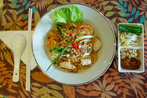 a plate of food with noodles and shrimp on a table at Kampong Thom Palace Hotel in Kompong Thom