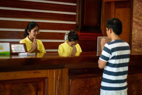 a boy and two girls sitting at a counter with a laptop at Kampong Thom Palace Hotel in Kompong Thom