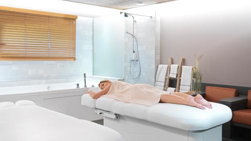 a woman laying on a bed in a bathroom at Le Parc Hôtel Obernai & Yonaguni Spa in Obernai