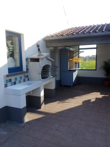 a patio with a fireplace and a bench in front of a house at Vakantiewoning De Wilg - rustig gelegen in Geraardsbergen