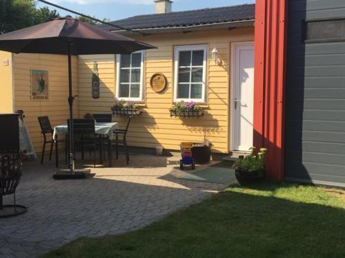 ein Haus mit einem Tisch und einem Sonnenschirm auf einer Terrasse in der Unterkunft Bed and Breakfast Nustrup in Vojens