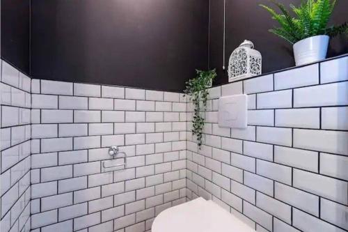 a white tiled bathroom with a toilet and plants at VERY CENTRAL DISNEYLAND apartment in Serris