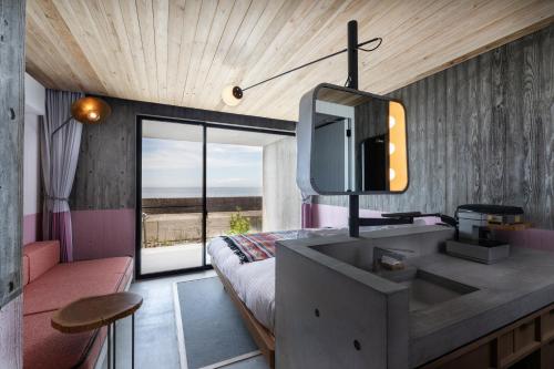 1 dormitorio con lavabo y 1 cama con ventana en KAMOME SLOW HOTEL, en Awaji