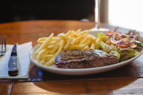 a plate of food with steak and french fries on a table at The Griffin Belle Hotel Vauxhall in London