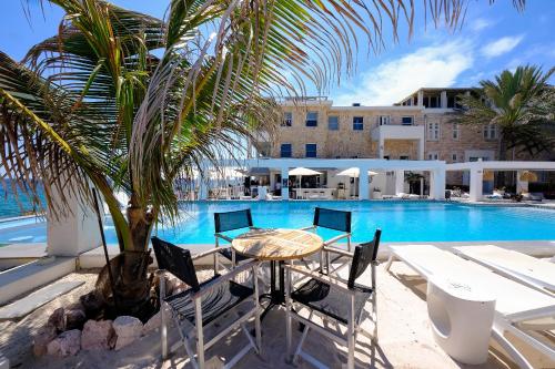 un patio con mesa y sillas junto a una piscina en Saint Tropez Boutique Hotel, en Willemstad