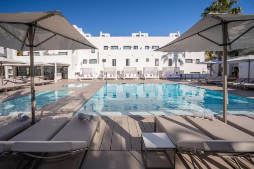 a hotel room with a pool table and chairs at Migjorn Ibiza Suites & Spa in Playa d'en Bossa