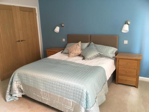 a bedroom with a bed with a blue wall at The Swallows in Seend