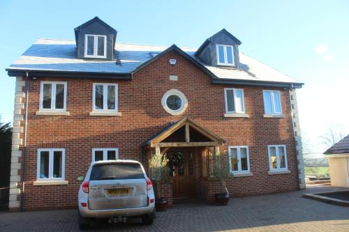 a car parked in front of a brick house at The Swallows in Seend