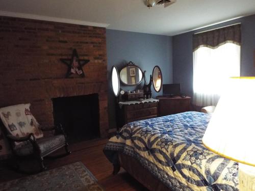 1 dormitorio con cama, chimenea y espejo en The Tillie Pierce House Inn, en Gettysburg