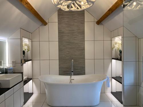 a white bathroom with a tub and a sink at The Wheatsheaf Hotel, Sandbach in Sandbach