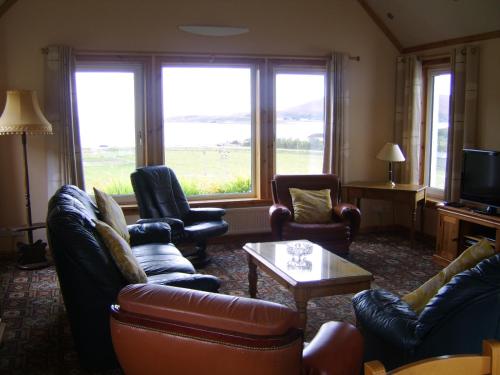 un soggiorno con divani, sedie e TV di Top House a Ullapool