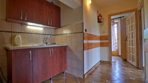 a kitchen with wooden cabinets and a tile floor at Dom Wczasowy Stanislawa in Biały Dunajec
