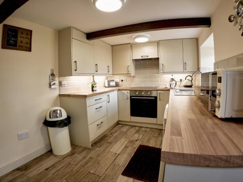 a large kitchen with white cabinets and wooden floors at Tower View in Blackburn