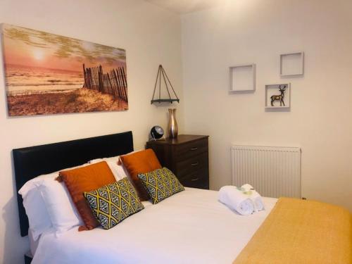 Budget Rooms @ Underwood Lane Crewe في كرو: غرفة نوم مع سرير أبيض مع وسائد برتقالية