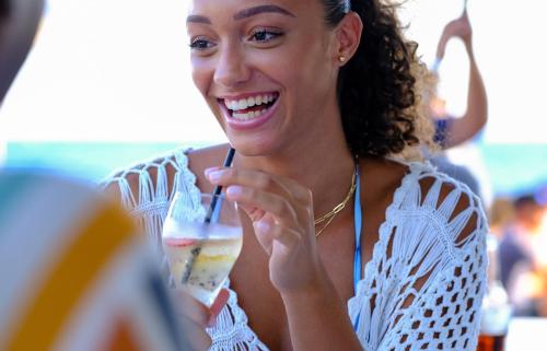 a woman is smiling while holding a drink at Saint Tropez Boutique Hotel in Willemstad