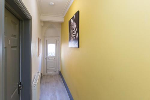 a hallway with a yellow wall and a white door at Crewe Rooms Brooklyn Street in Crewe