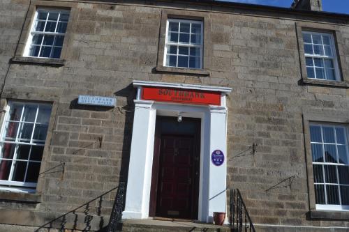 a brick building with a red sign above a door at Southbank Guesthouse in Elgin