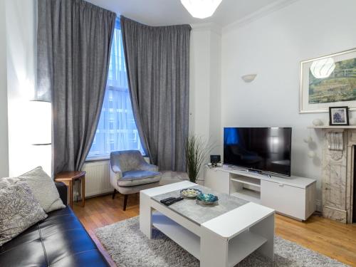 a living room with a couch and a tv at Spacious 1 Bed in West Kensington or Hammersmith in London