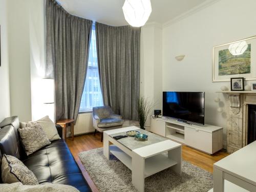 a living room with a couch and a tv at Spacious 1 Bed in West Kensington or Hammersmith in London