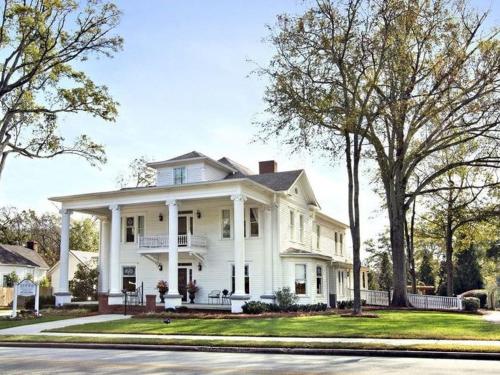 une grande maison blanche avec des arbres devant elle dans l'établissement Sparrow Grove Manor, à Monroe