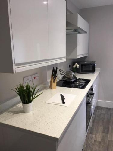 Townhouse @ Corporation Street Stoke في ستوك أون ترينت: مطبخ بدولاب بيضاء وقمة كونتر