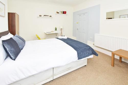 a white bedroom with a white bed with blue pillows at Townhouse @ Earle Street Crewe in Crewe