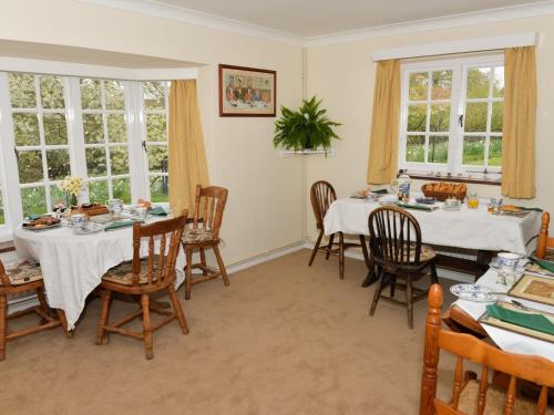 a dining room with two tables and chairs and windows at Twyford Farm B&B in Haywards Heath