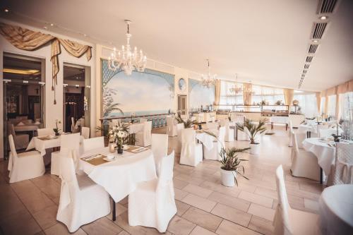 a restaurant with white tables and chairs and a chandelier at Hotel Zur Heimat in Weiden