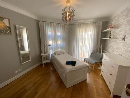 a bedroom with a bed and a chair and a chandelier at Top villa with extraordinary view of Atlantic in São Martinho do Porto