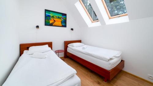 two beds in a room with white walls and windows at Apartamenty EverySky - Wyspiańskiego 4-4a in Karpacz