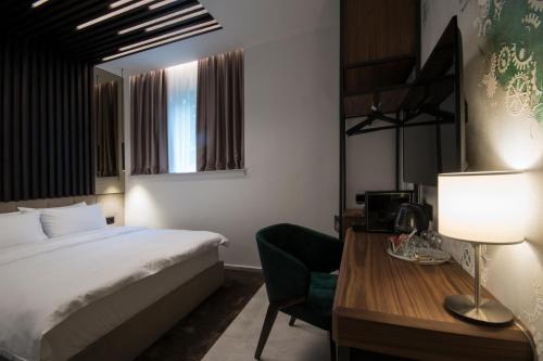 a hotel room with a bed and a desk with a chair at The Location Hotel in Belgrade