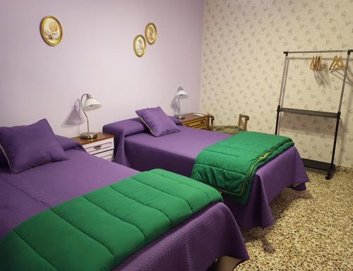 two beds in a room with purple and green at Casa La Remolina in Casas Ibáñez
