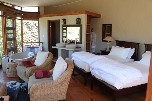 a bedroom with two beds and chairs and a bathroom at Sederkloof Lodge in Studtis