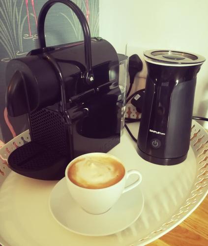 a cup of coffee on a plate next to a coffee maker at Four Seasons Guesthouse in Castleton